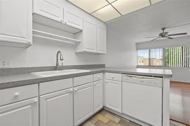 a kitchen with white cabinets and sink
