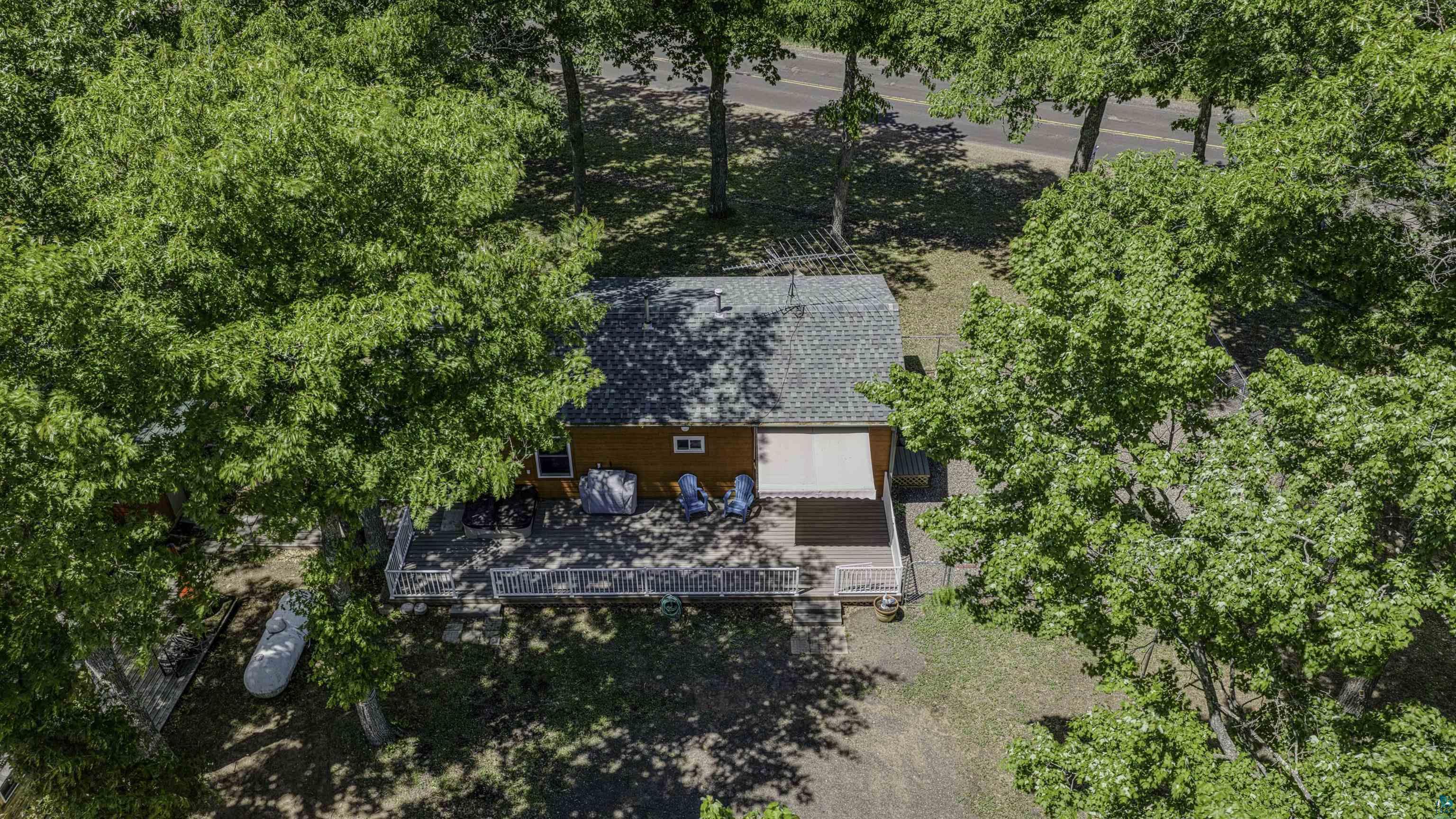 66075 Rooster Road Iron River, WI 54847 - Photo 5 of 52 Aerial property view showcasing a residence with a shingle roof, a wrap-around deck with white railings, and a retractable awning