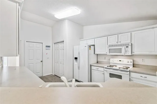 a kitchen with white cabinets and appliances