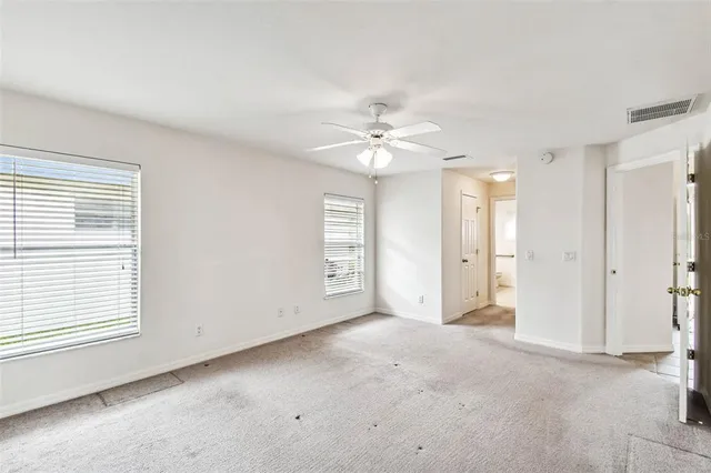 an empty room with windows and fan