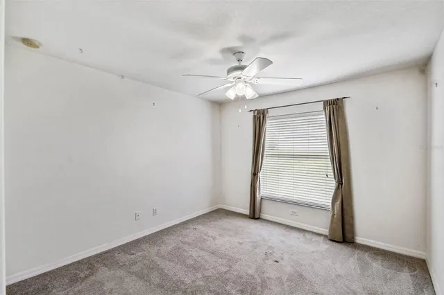 an empty room with windows and fan