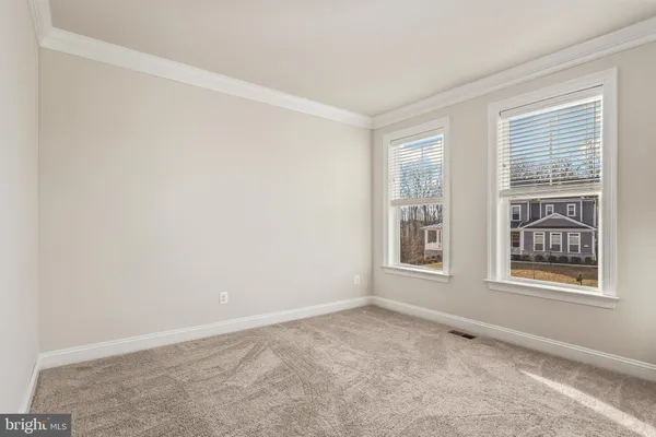 a view of a room with wooden floor fridge and windows