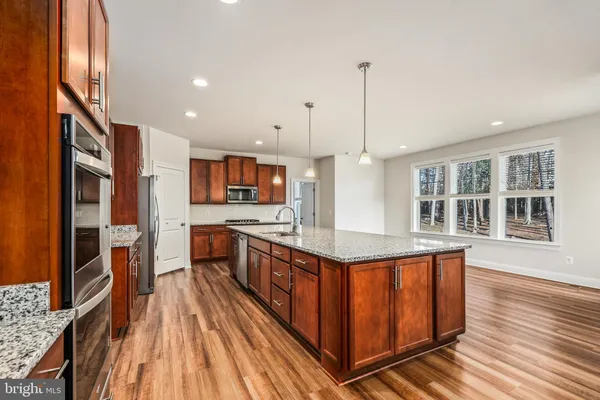 a large kitchen with stainless steel appliances granite countertop a stove and a wooden floors
