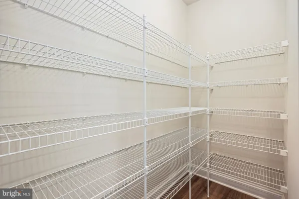 a living room with stainless steel appliances furniture wooden floor and a kitchen view