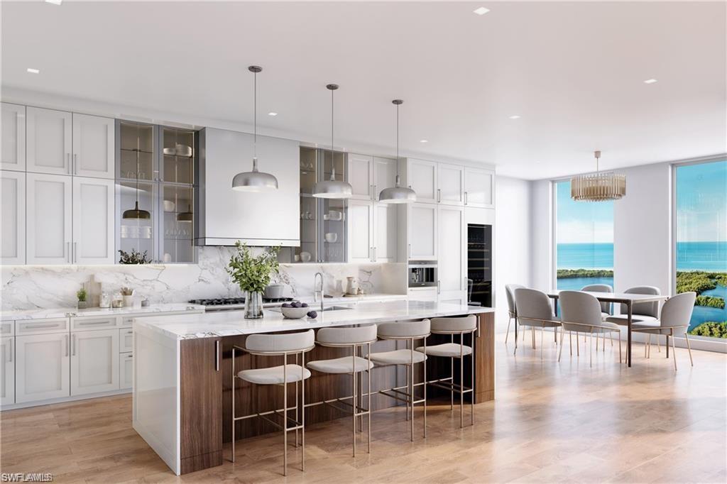 6869 Grenadier Boulevard, Unit 402 Naples, FL 34108 - Photo 12 of 12 Kitchen with hanging light fixtures, an island with sink, and a kitchen bar