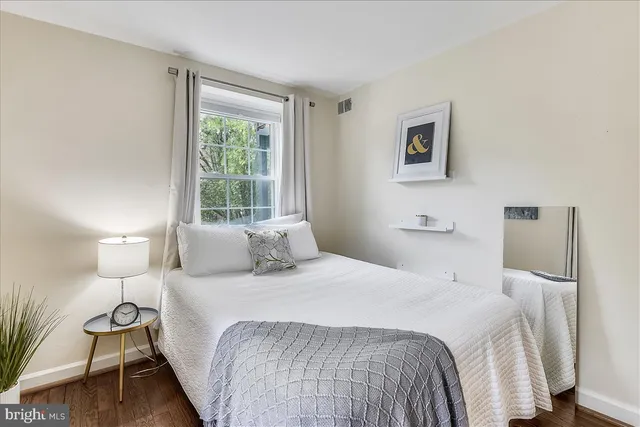 a bedroom with a bed and a lamp with wooden floor