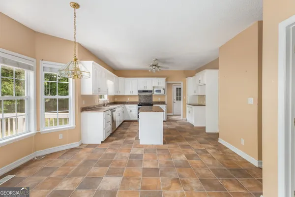 a kitchen with stainless steel appliances kitchen island granite countertop a refrigerator a sink a oven and a view of living room