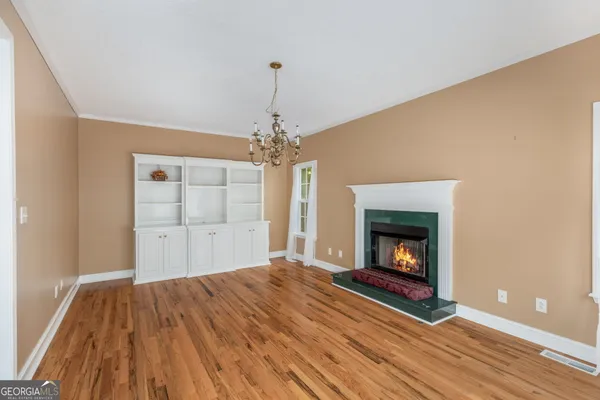 a view of an empty room with wooden floor fireplace and a window