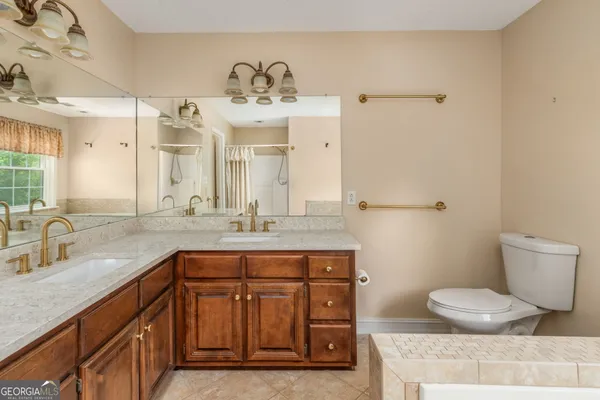 a bathroom with a granite countertop sink a toilet and a mirror
