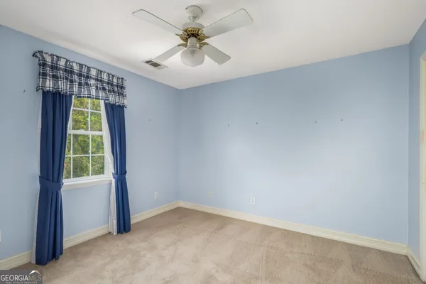 an empty room with a window and a ceiling fan