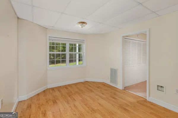 an empty room with wooden floor and windows