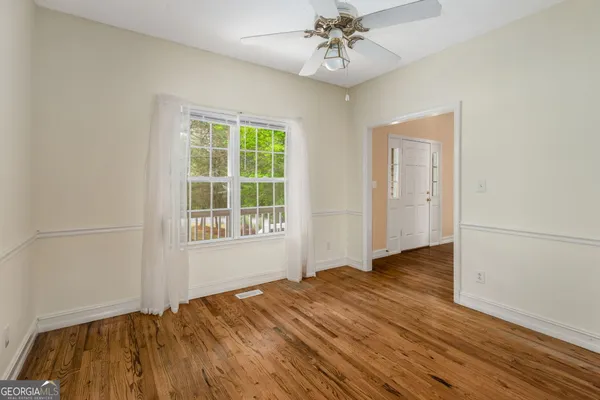 a view of an empty room with wooden floor and a window
