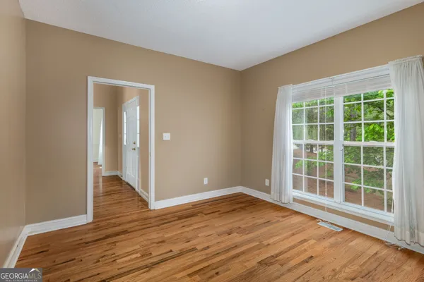 a view of an empty room with wooden floor and a window