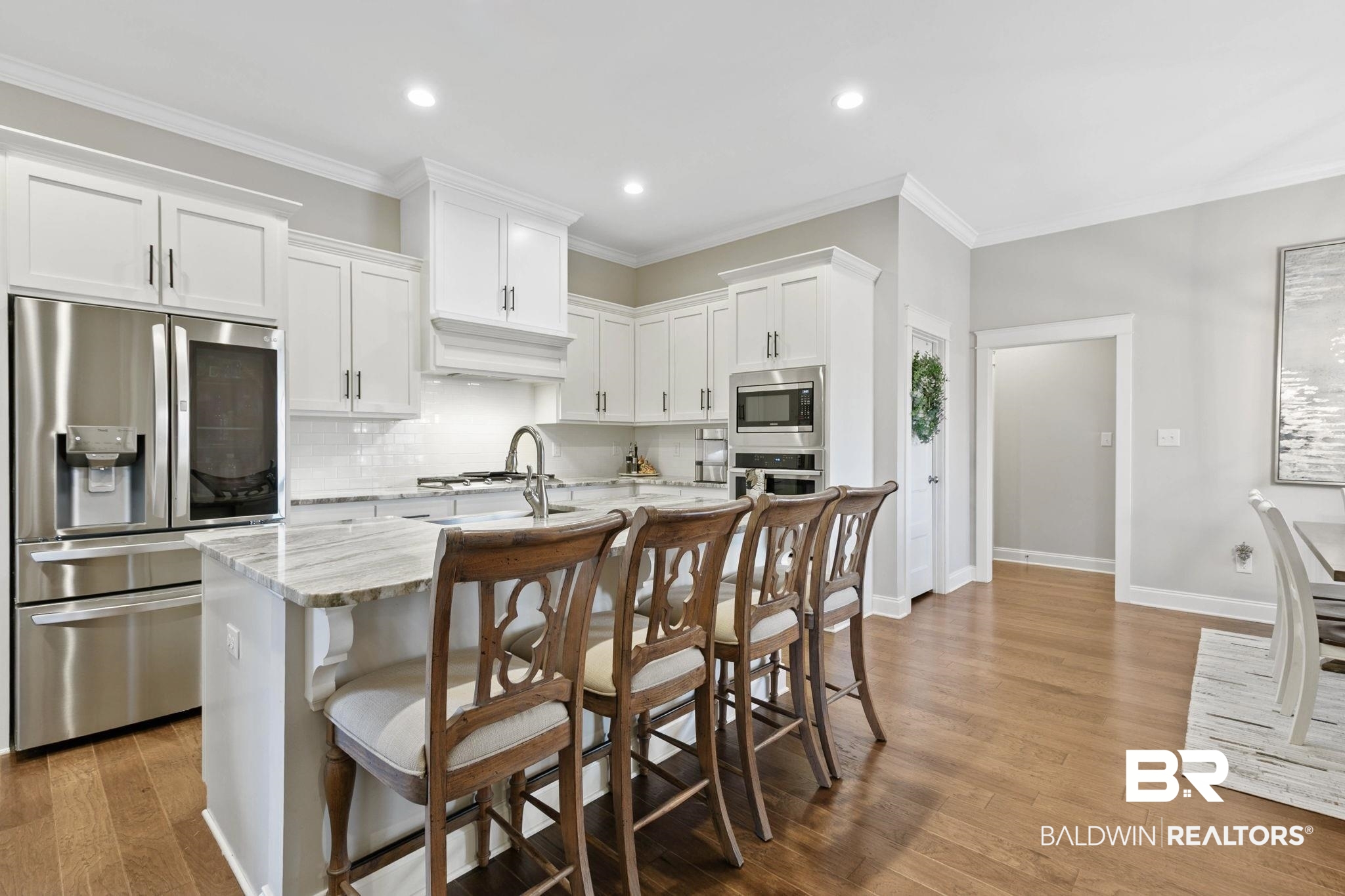 291 Hemlock Drive Fairhope, AL 36532 - Photo 14 of 65 Kitchen featuring stainless steel appliances, white cabinets, a breakfast bar, a center island with sink, and light stone countertops