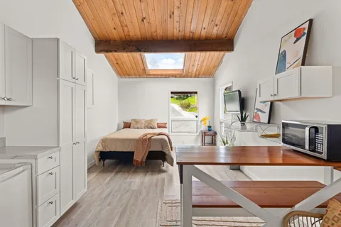 a living room with stainless steel appliances furniture a fireplace and a kitchen view
