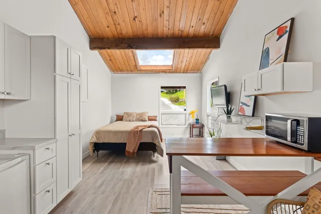 a living room with stainless steel appliances furniture a fireplace and a kitchen view