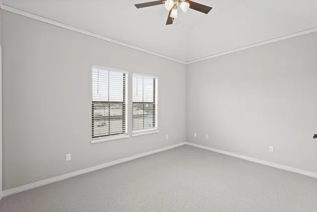 an empty room with chandelier fan and windows