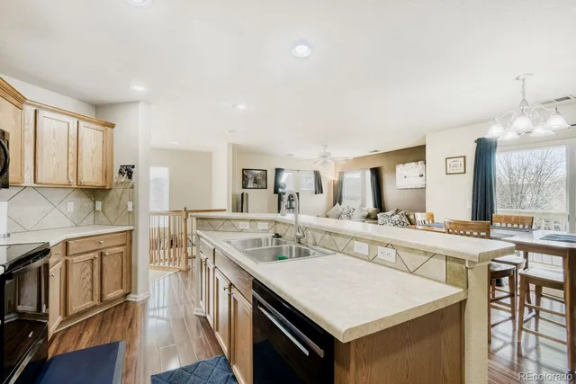 a kitchen with stainless steel appliances granite countertop a stove a sink dishwasher and white cabinets with wooden floor