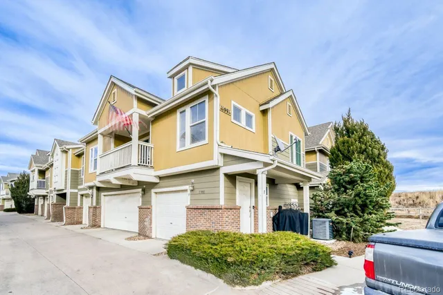 a view of a white building among the street with plants and large trees