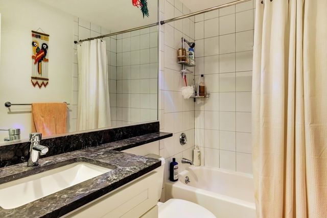 a bathroom with a granite countertop sink a toilet and shower