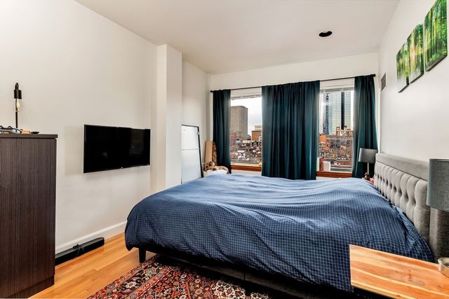 a bedroom with a bed and a flat tv screen on dresser