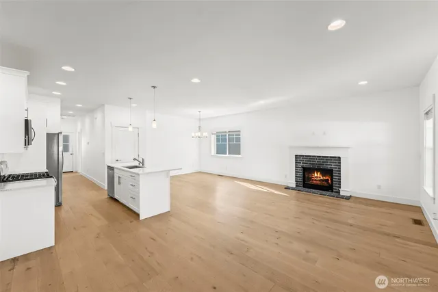 an empty room with kitchen view and a fireplace