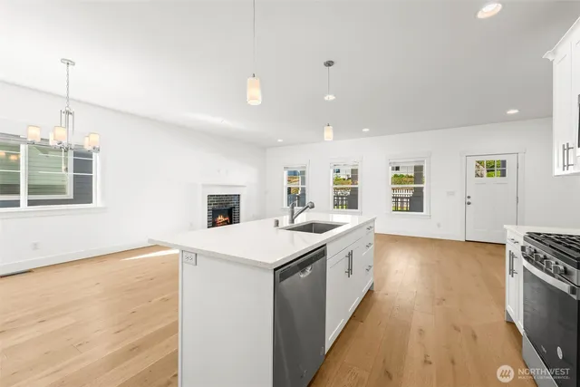 a kitchen with stainless steel appliances granite countertop a sink a stove and a wooden floors