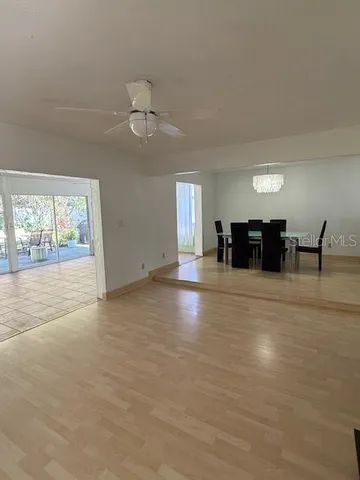 an empty room with chandelier fan and windows