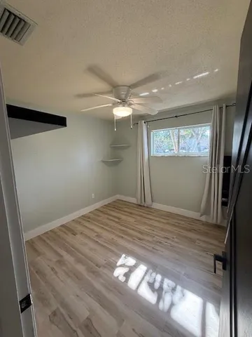 a view of empty room with window and wooden floor