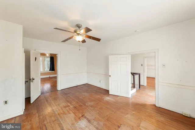a view of empty room with wooden floor and ceiling fan