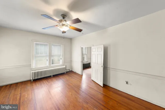 an empty room with wooden floor fan and windows