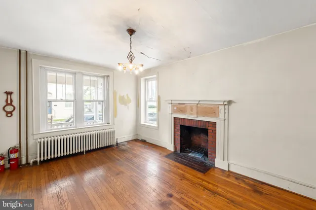 an empty room with wooden floor fireplace and windows