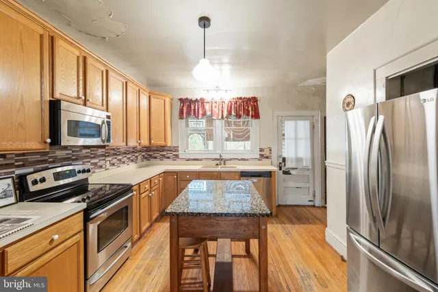 a kitchen with stainless steel appliances granite countertop a stove refrigerator and a sink
