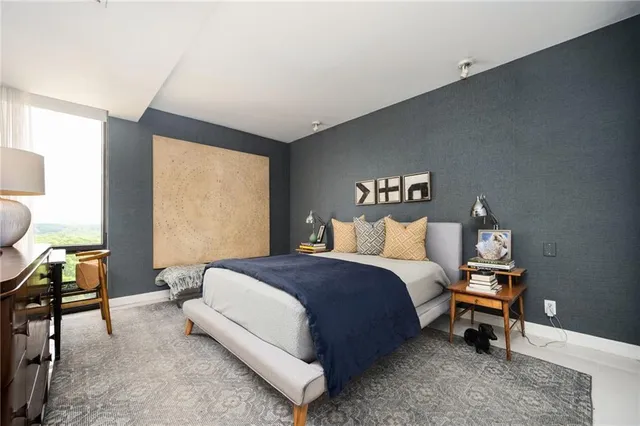 a spacious bedroom with a bed and a lamp on wall