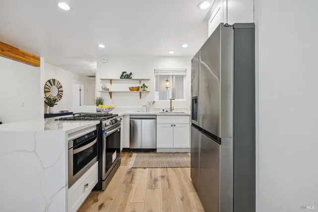 a kitchen with kitchen island a stove a refrigerator and a dining table with wooden floor