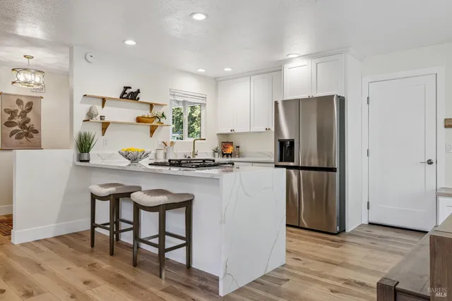 a kitchen with stainless steel appliances granite countertop a stove and white cabinets with wooden floor