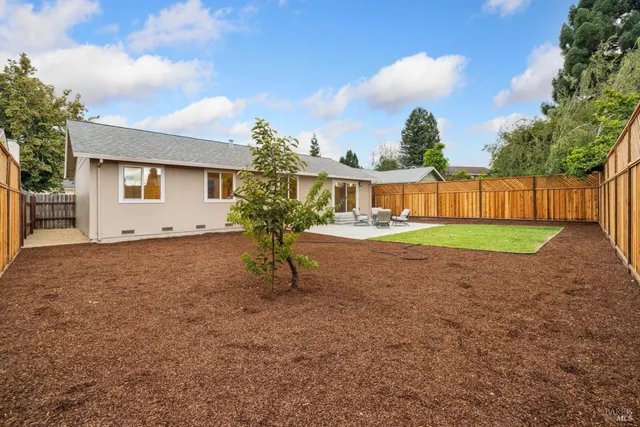 a view of backyard of house with outdoor seating and covered with trees
