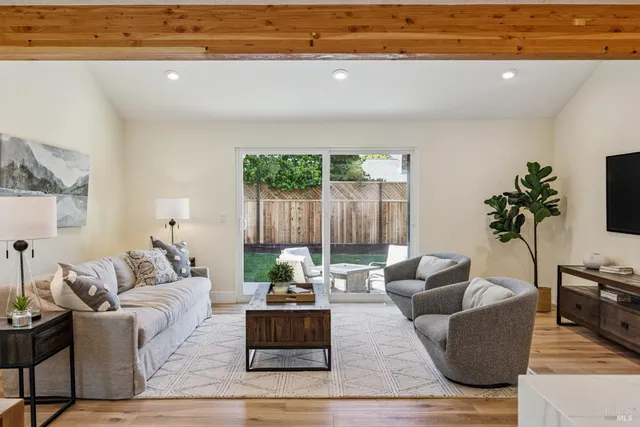 a living room with couches and kitchen view with wooden floor