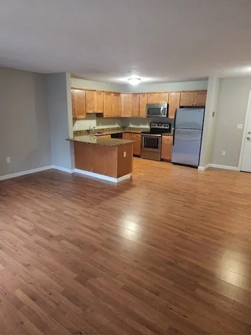 a large kitchen with stainless steel appliances granite countertop a large counter top and a stove with wooden floor