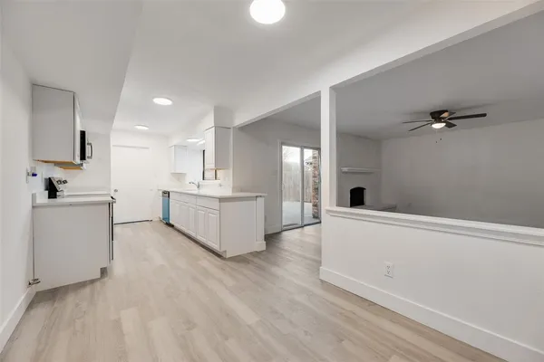 a large white kitchen with a sink dishwasher a stove and white cabinets with wooden floor