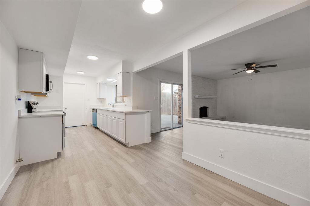 4512 Larner Street The Colony, TX 75056 - Photo 13 of 29 a large white kitchen with a sink dishwasher a stove and white cabinets with wooden floor