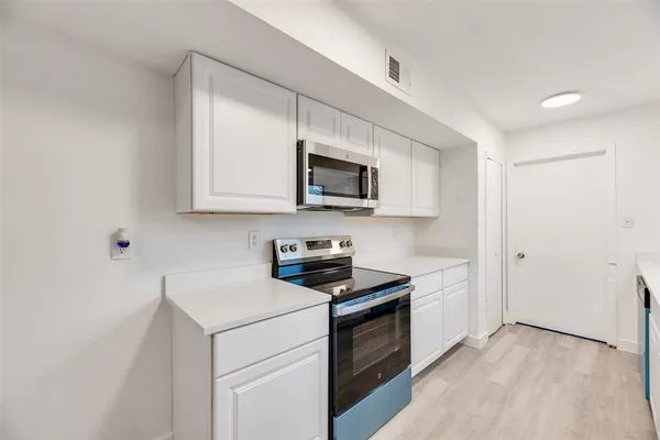 a kitchen with stainless steel appliances granite countertop white cabinets a stove top oven a sink and dishwasher