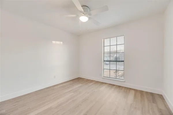 an empty room with wooden floor ceiling fan and windows