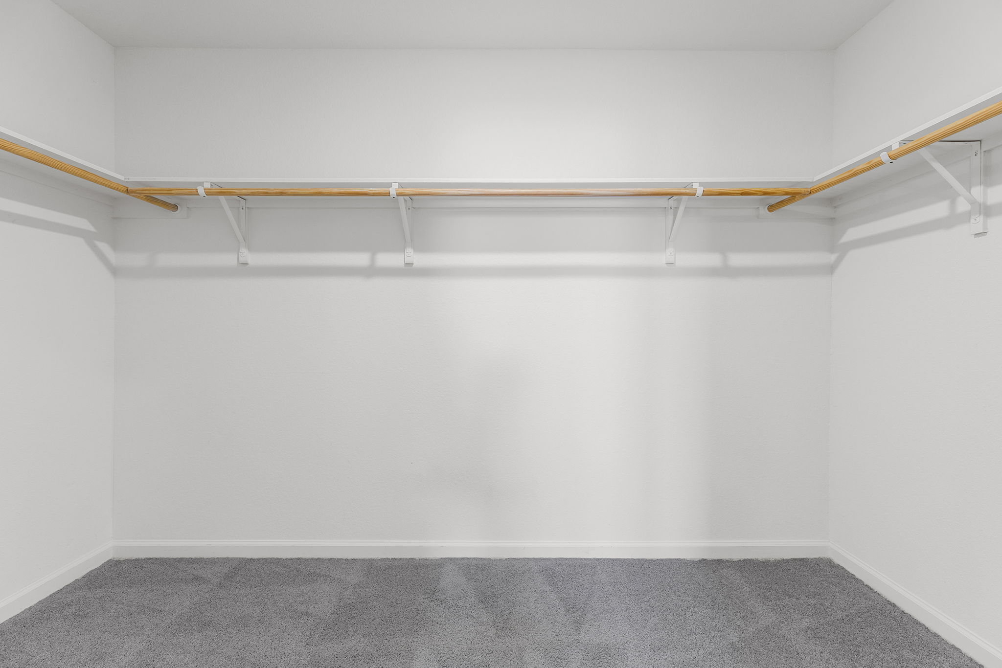 409 Line Of Fire Way Jarrell, TX 76537 - Photo 22 of 30 Walk-in closet featuring light gray carpeting, white walls, built-in wood-finish shelving, hanging rods, and open storage space.