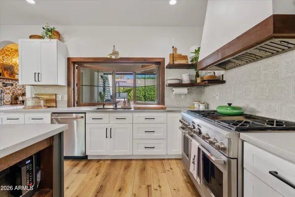 a kitchen with stainless steel appliances granite countertop a stove a sink and a microwave