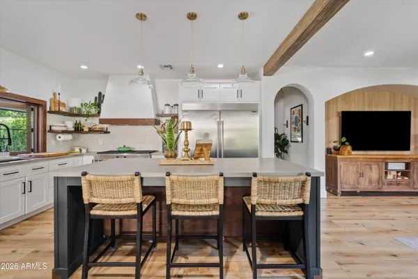 a kitchen with stainless steel appliances kitchen island granite countertop a stove a sink a dining table and chairs with wooden floor