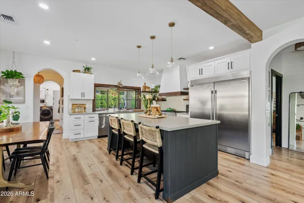 a kitchen with stainless steel appliances a dining table chairs stove refrigerator and cabinets