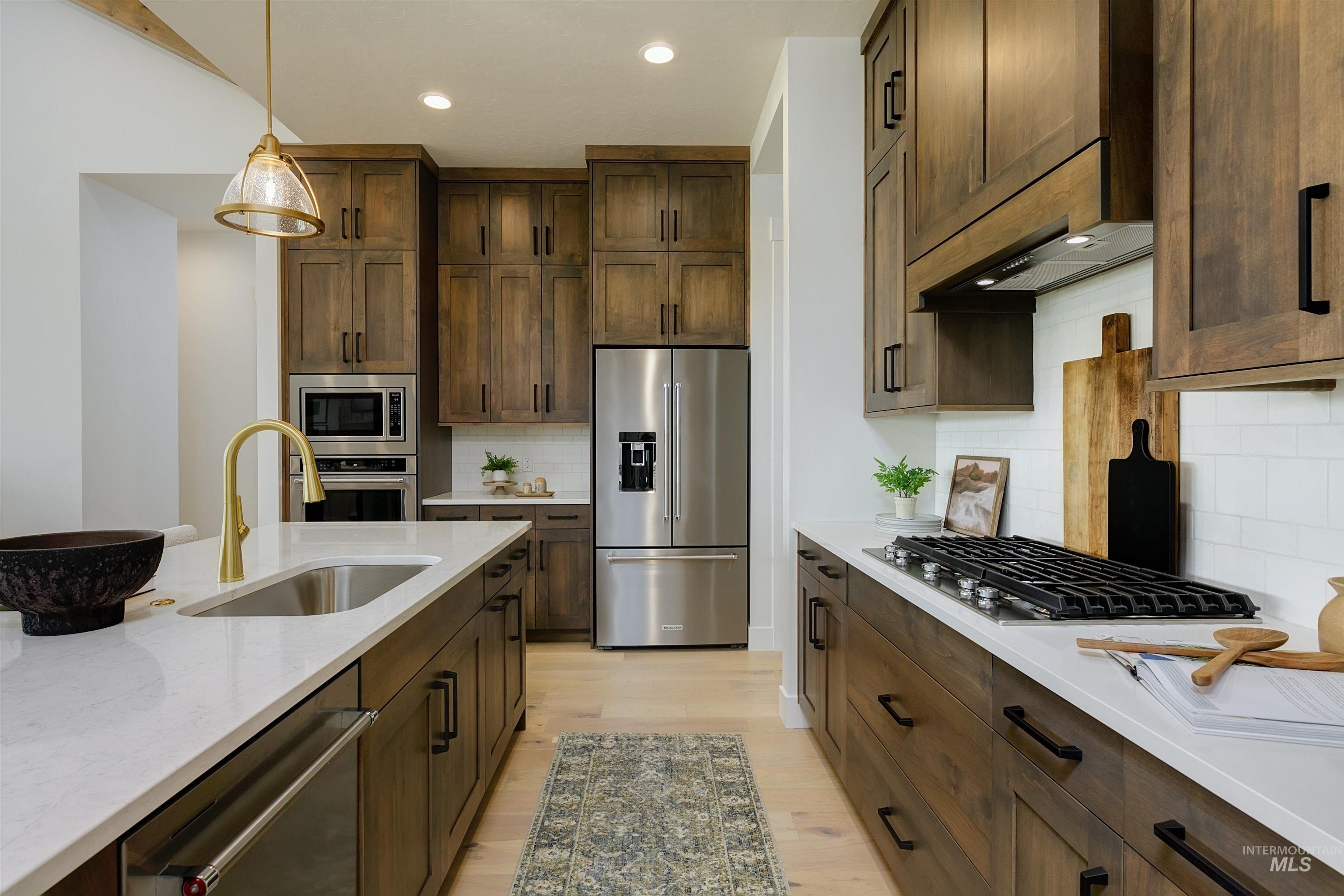 11468 South Saylis Place Kuna, ID 83634 - Photo 8 of 38 Kitchen with stainless steel appliances, light wood finished floors, light stone counters, pendant lighting, and decorative backsplash