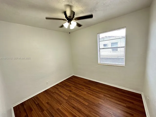 a view of a room with wooden floor and a ceiling fan