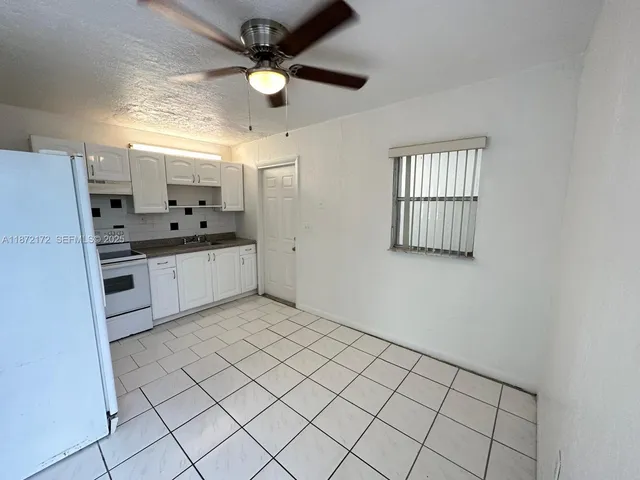 a large white kitchen with a sink a window and stainless steel appliances
